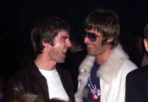 Reunião do Oasis: Noel e Liam Gallagher sorrindo um para o outro no NME Awards em 2001