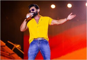 O cantor Pablo canta com óculos escuros e camiseta amarela