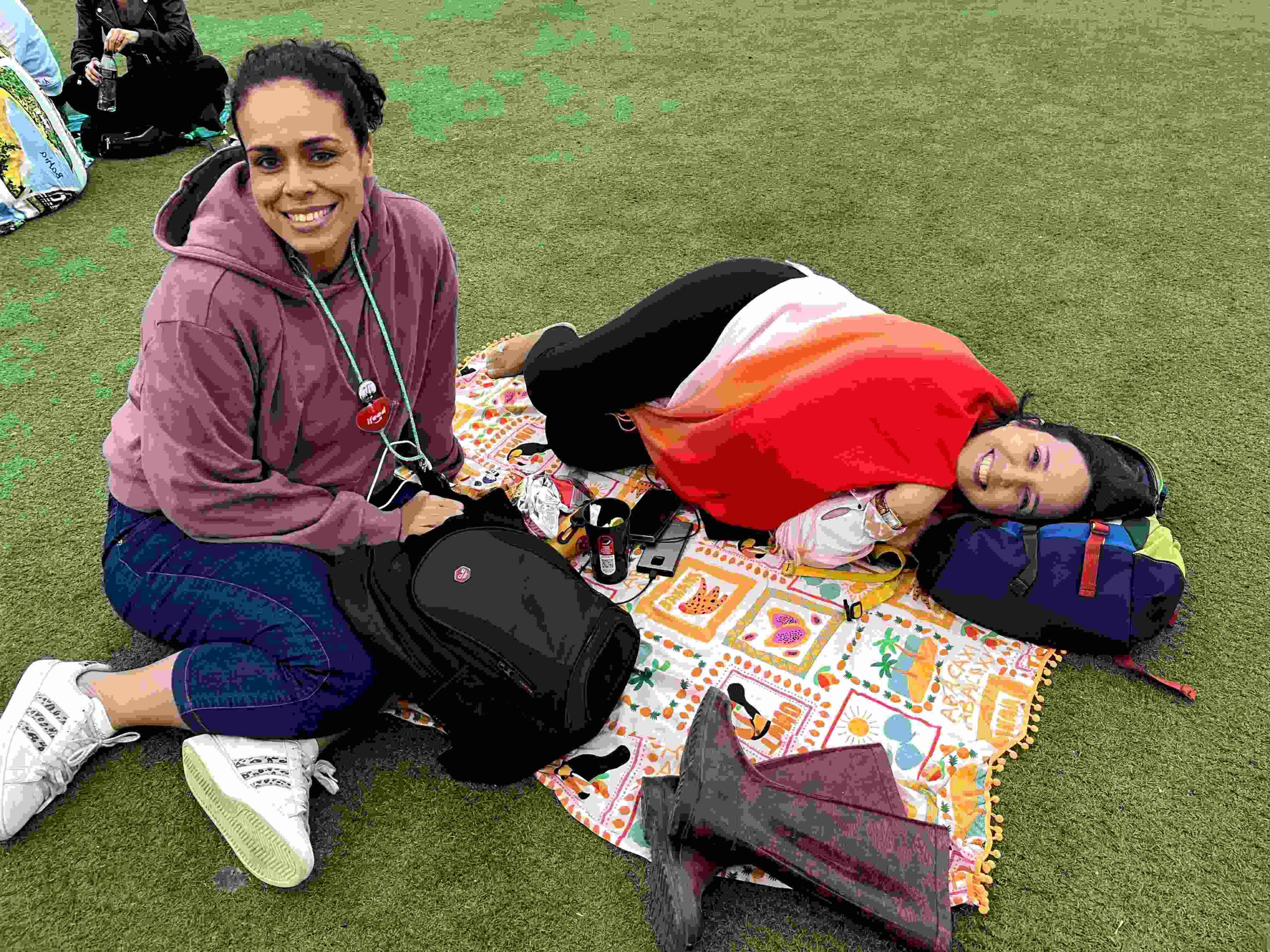 As amigas Amanda Meireles, 41, e Michele Joia, 43, também aproveitaram o espaço de tempo entre shows para deitar em uma canga no gramado. Um puff cairia bem, né? (Foto: Vitória Zane)